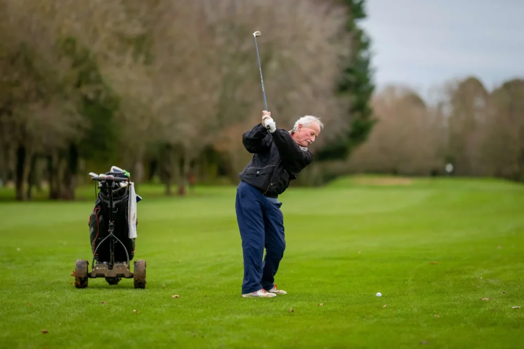Am old man playing golf.