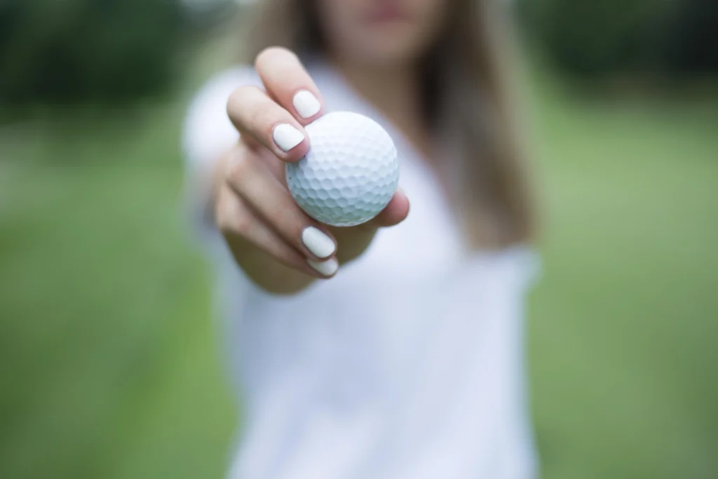 A girl having a golf ball in her hand.